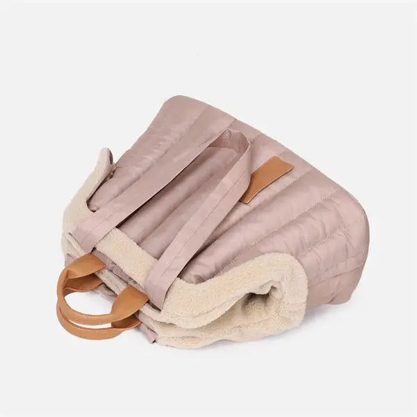 Pet handbag carrier with insulated material and soft plush lining for warmth and comfort.